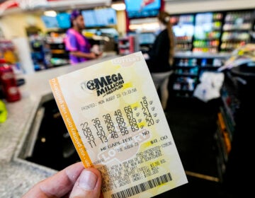 A person holds up a lottery ticket