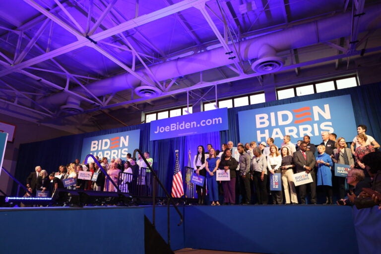 People on a stage with a sign reading Biden Harris