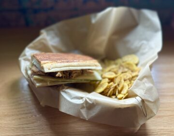 A half portion of the Chibano sandwich--roast pork simmered in special marinade, with ham, cheese and Chinese pickles--served with mojo-spice blend plantain chips.