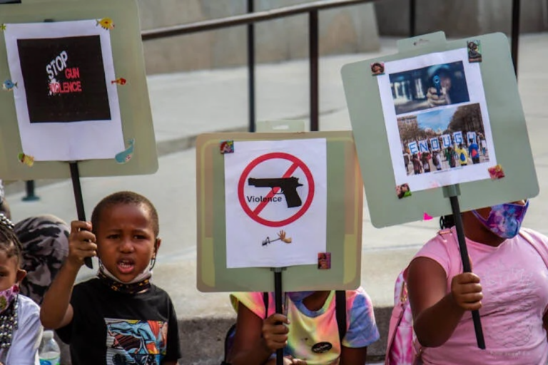 A group of kids from the Southwest Philadelphia Healthnastics program, ages 3-18, held signs at a protest demanding the Kenney administration do more to address gun violence in the city on Aug. 4, 2021. (Kimberly Paynter/WHYY)