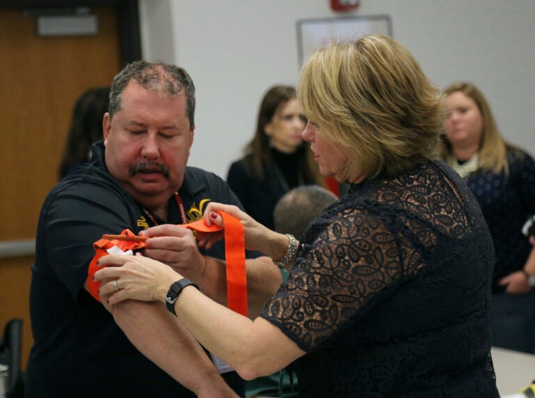 One person applying a tourniquet to another's arm