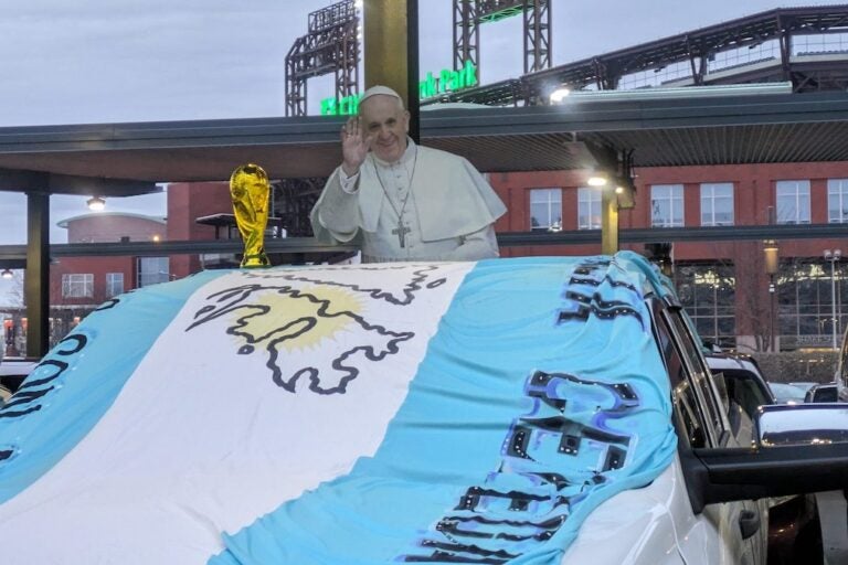 A car at the tailgate before Argentina's exhibition match against El Salvador is decorated with replicas of Pope Francis and the FIFA World Cup trophy.