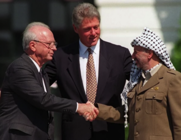 Bill Clinton looks on as Yitzhak Rabin and Yasser Arafat shake hands