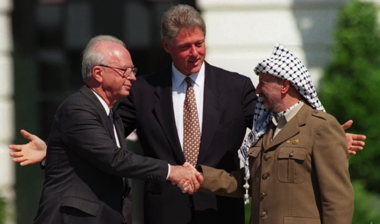 Bill Clinton looks on as Yitzhak Rabin and Yasser Arafat shake hands