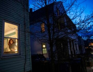 McKenna Shuster is visible through a window working in her house at twilight.