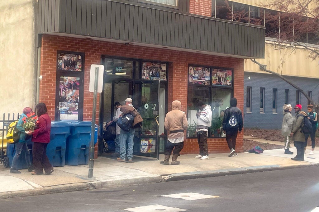People hanging out on the sidewalk in front of the building's entrance.