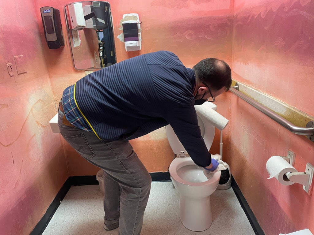 Michael Kalmbach cleaning a toilet
