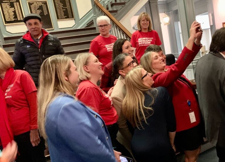 Moms Demand Action group in red shirts take a selfie with lawmakers