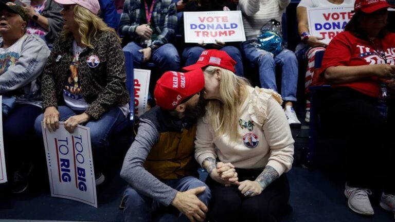 A couple kisses while waiting for the start of a campaign rally with former President Donald Trump on March 9 in Rome, Ga.