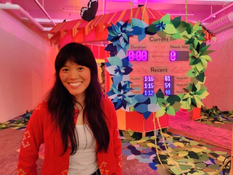 Artist Risa Puno on the floor of her Whac-a-Mole game, in her installation 