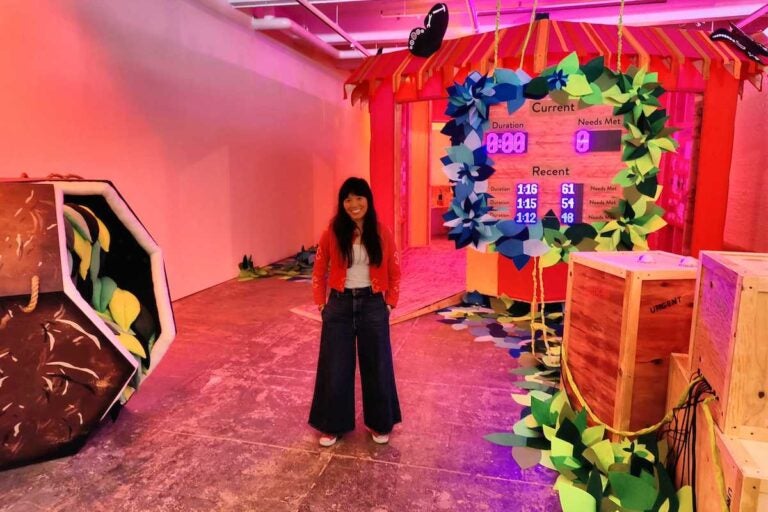 Artist Risa Puno on the floor of her Whac-a-Mole game, in her installation 