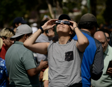 A woman watches an annular solar eclipse on Oct. 14, 2023 using special solar filter glasses at the National Autonomous University of Mexico.