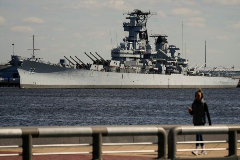 A person walks in Philadelphia across the Delaware River from the USS New Jersey in Camden, N.J., Tuesday, March 19, 2024.