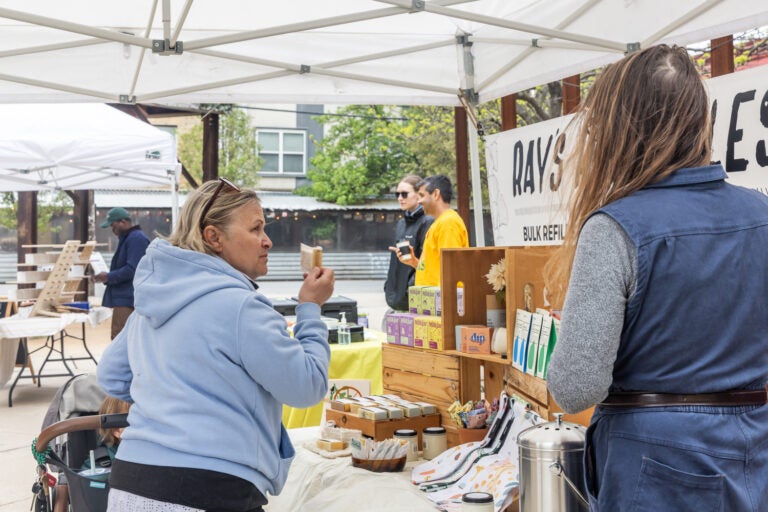 Fran Campbell smells one of Ray’s shower steamers before purchasing at the Northern Liberties Farmers’ Market on April 13, 2024. (Kimberly Paynter/WHYY)