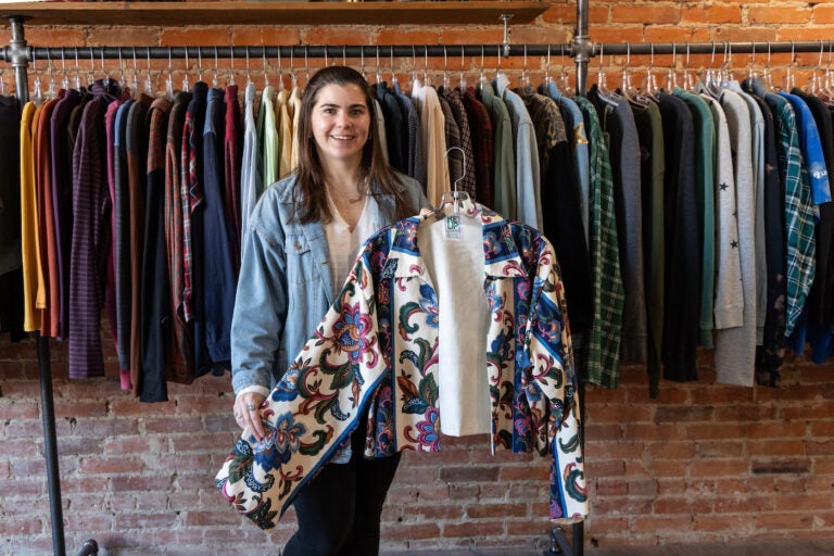 ReUp Fashion store owner Tara Martinak with a coat she made from thrifted curtains in her store in Haddon Township, N.J. (Kimberly Paynter/WHYY)