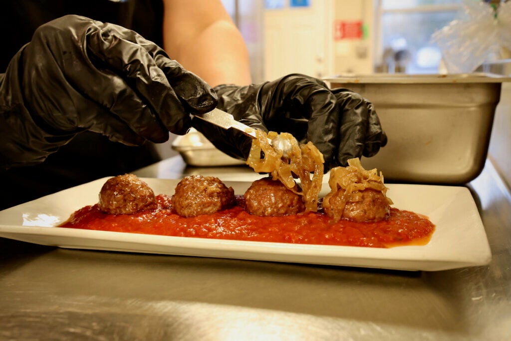 Vegan meatballs are topped with carmelized shallots at LesbiVeggies in Audubon, N.J. (Emma Lee/WHYY)