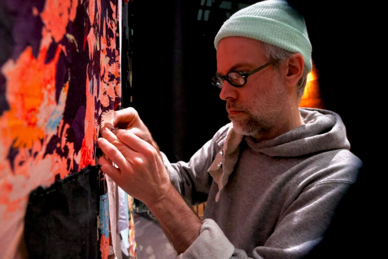 Set designer Steven Dufala adds pieces of fabric to the hand-sewn curtain on the set of ''The Good Person of Setzuan'' at Wilma Theater. (Emma Lee/WHYY)