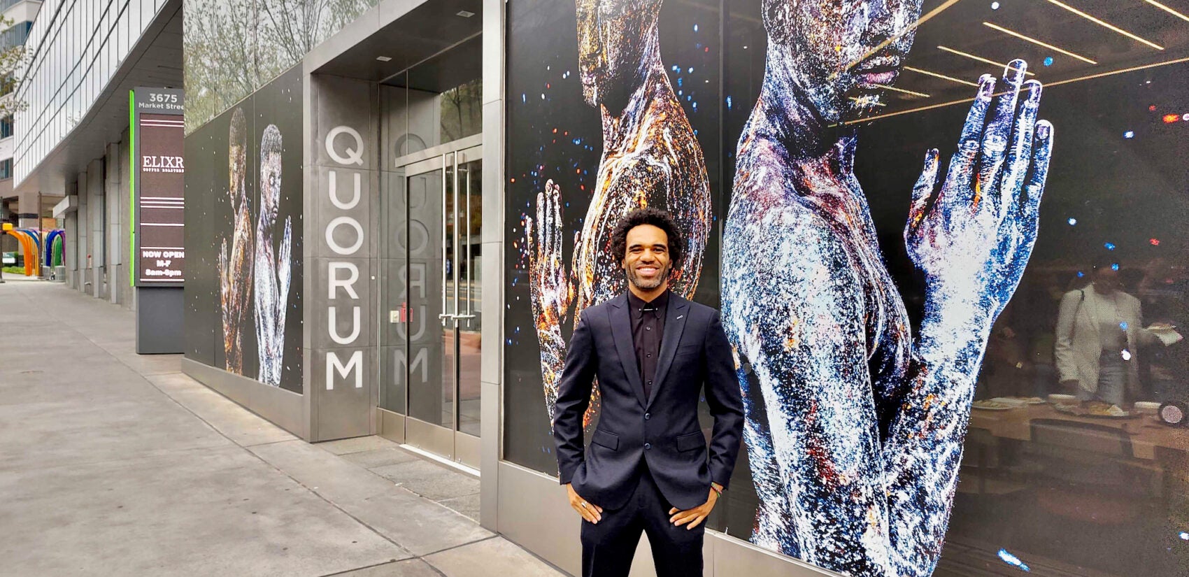 Mikael Owunna in front of his mural on the entrance to the University City Science Center