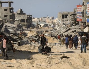 People walk past destroyed buildings along a road in Khan Younis on April 7, 2024
