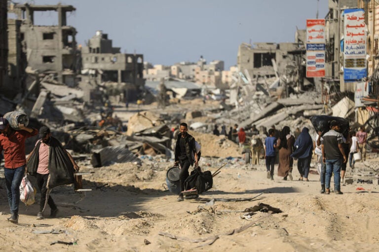 People walk past destroyed buildings along a road in Khan Younis on April 7, 2024