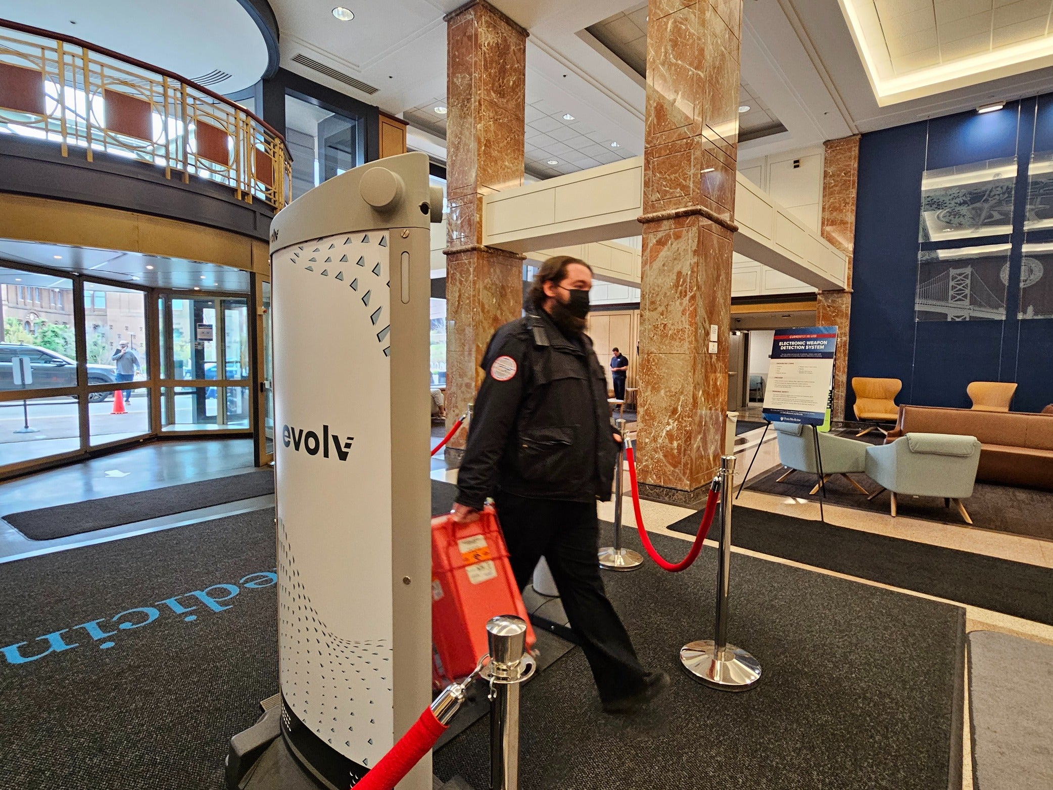 A security guard walks through the Evolv weapons detection security system in the main lobby at the Hospital of the University of Pennsylvania