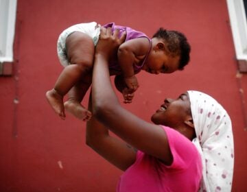 A mother holds her daughter in the air.