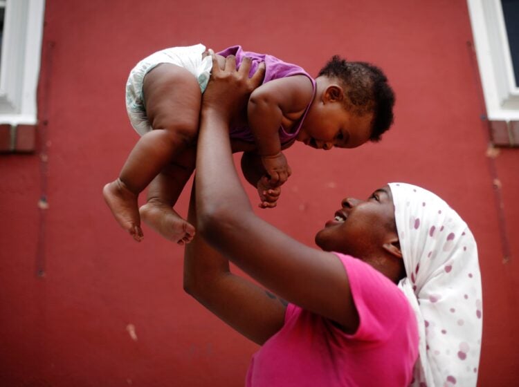 A mother holds her daughter in the air.