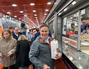 David McCormick orders several Philly cheesesteaks from the window at Geno’s Steaks in South Philly. (Carmen Russell-Sluchansky/WHYY)