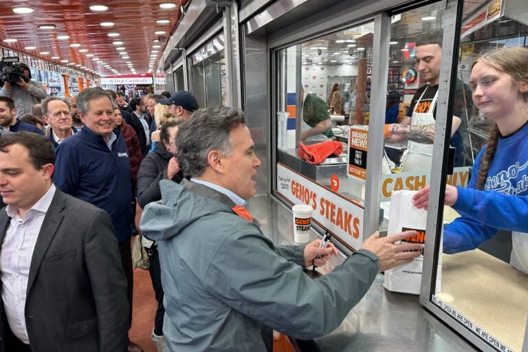 David McCormick orders several Philly cheesesteaks fromthe window at Geno’s Steaks in South Philly. (Carmen Russell-Sluchansky/WHYY)