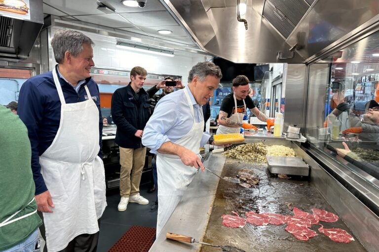 National Republican Senate Committee Chairman Steve Daines of Montana watches as Republican Senate candidate David McCormick grills steaks at Geno’s in South Philly. (Carmen Russell-Sluchansky/WHYY)