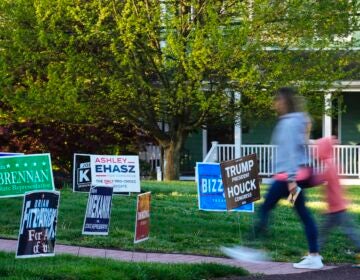 A voter and child walk past campaign signs posted outside of a polling site in Doylestown, Pa.