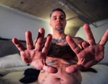 Diego López displays his hands, the left hand bearing the absence of a finger lost to a bullet. (Aníbal Martel for palabra)