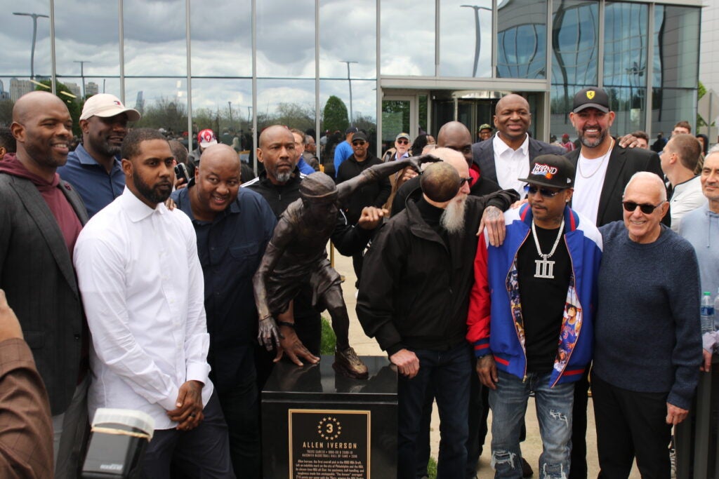 Allen Iverson and his former teamates posing next to the statue