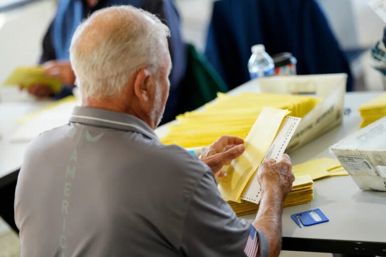 A person puts a ballot in an envelope