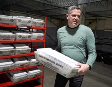 Allegheny County Election Division Deputy Manager Chet Harhut carries a container of mail-in ballots in Pittsburgh