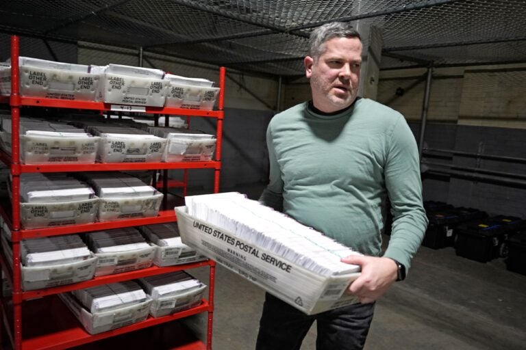 Allegheny County Election Division Deputy Manager Chet Harhut carries a container of mail-in ballots in Pittsburgh