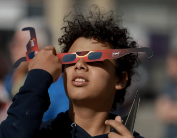 Junior Espejo looks through eclipse glasses