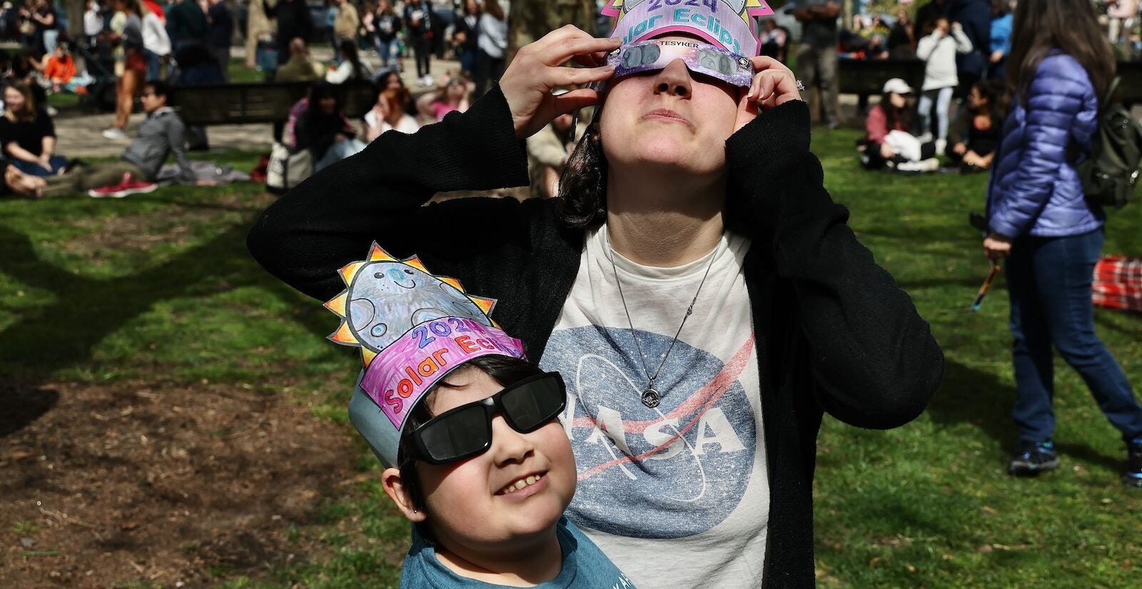 Kasey Moore and 8-year-old daughter, Sadie, from Northeast Philadelphia wear homemade hats as they watch the eclipse outside the Franklin Institute in Center City