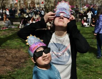 Kasey Moore and 8-year-old daughter, Sadie, from Northeast Philadelphia wear homemade hats as they watch the eclipse outside the Franklin Institute in Center City