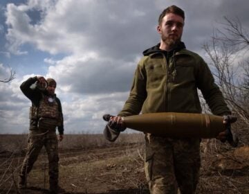 Ukrainian soldiers carry shells to fire
