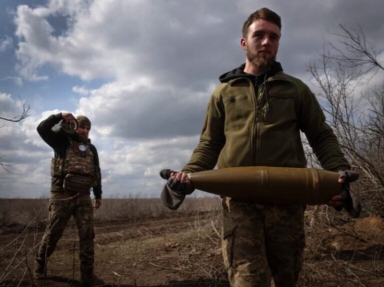 Ukrainian soldiers carry shells to fire