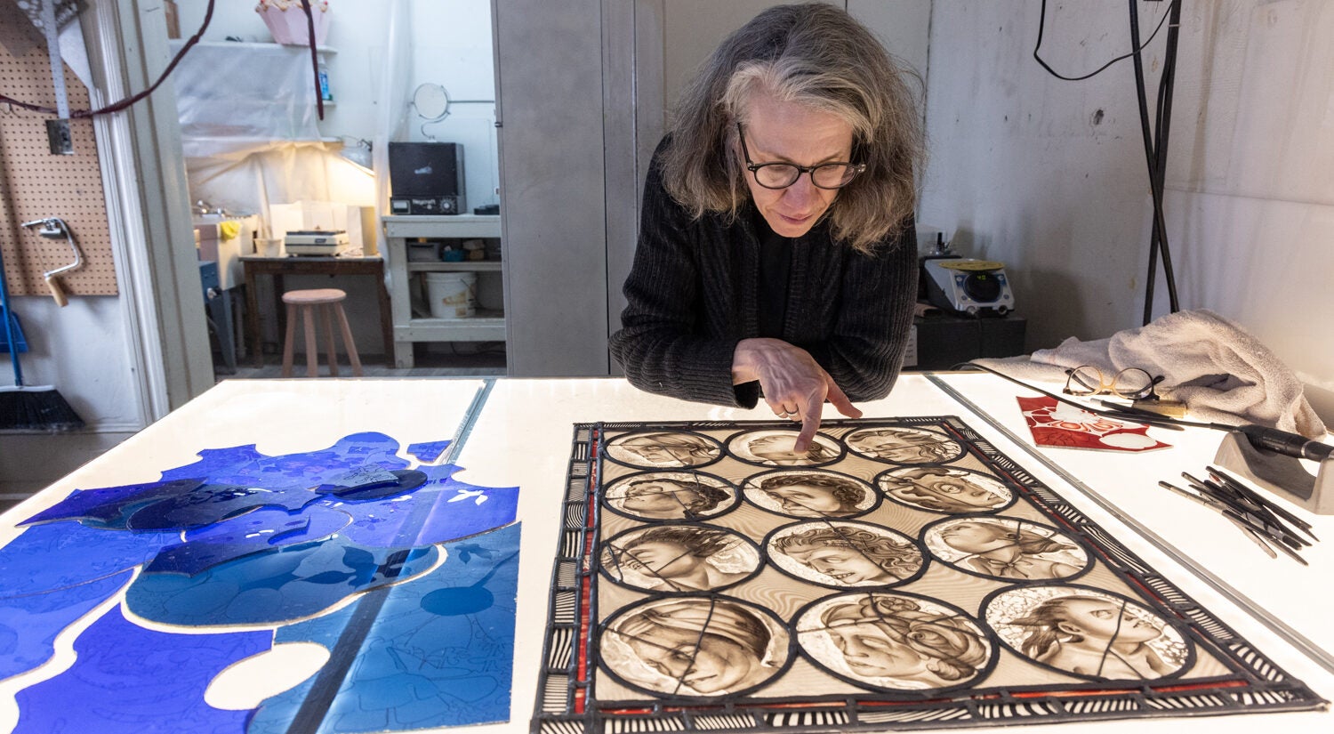 Judith Schaechter points to her work on her desk