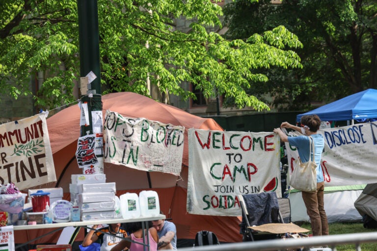Members of a protest encampment at UPenn hang signs around their camp on May 1, 2024.