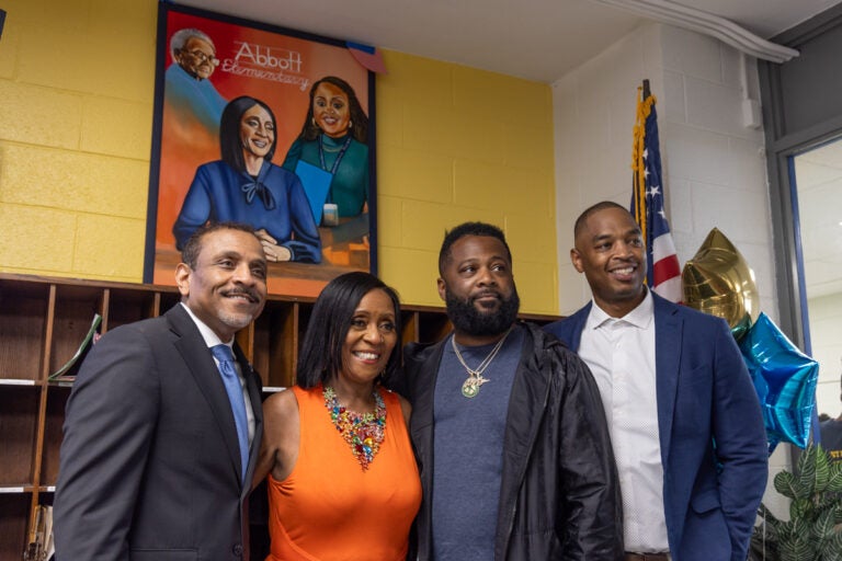 Philadelphia Superintendent Dr. Tony Watlington (left); retired teacher Joyce Abbott (center-left); painter Ivben Taqiy (center-right); and Andrew Hamilton School principal Torrence Rothmiller (right), in front of Taqiy’s portrait of Abbott, her mother and former student Quinta Brunson, who created the show 