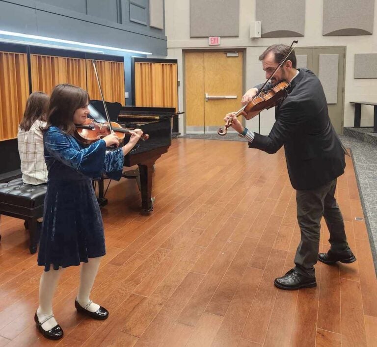 Serban Petrescu and Tatyana Roytshteyn’s younger daughter, Alexandra (9) in this photo at a studio recital, with their older daughter Beatrice playing the piano at Widener University. (Courtesy of Serban Petrescu and Tatyana Roytshteyn)