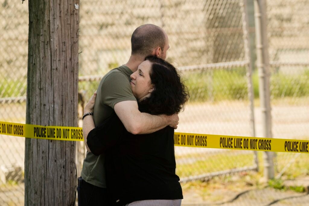 People embrace near the scene of a fatal shooting at Delaware County Linen in Chester, Pa., Wednesday, May 22, 2024.