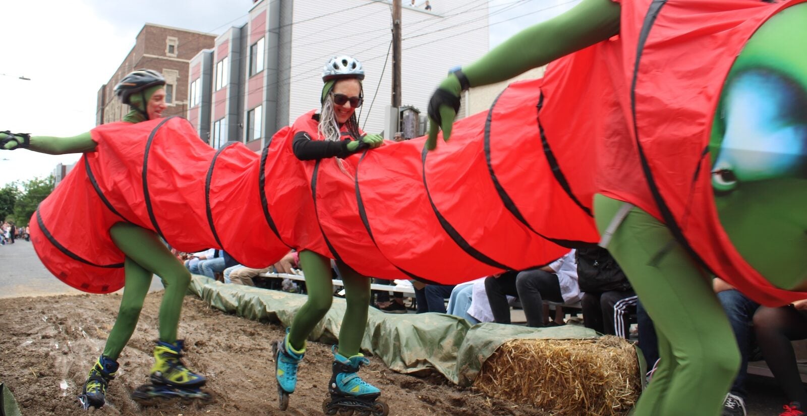 Kensington Derby participants dressed as a caterpillar on roller skates ride through the mud pit