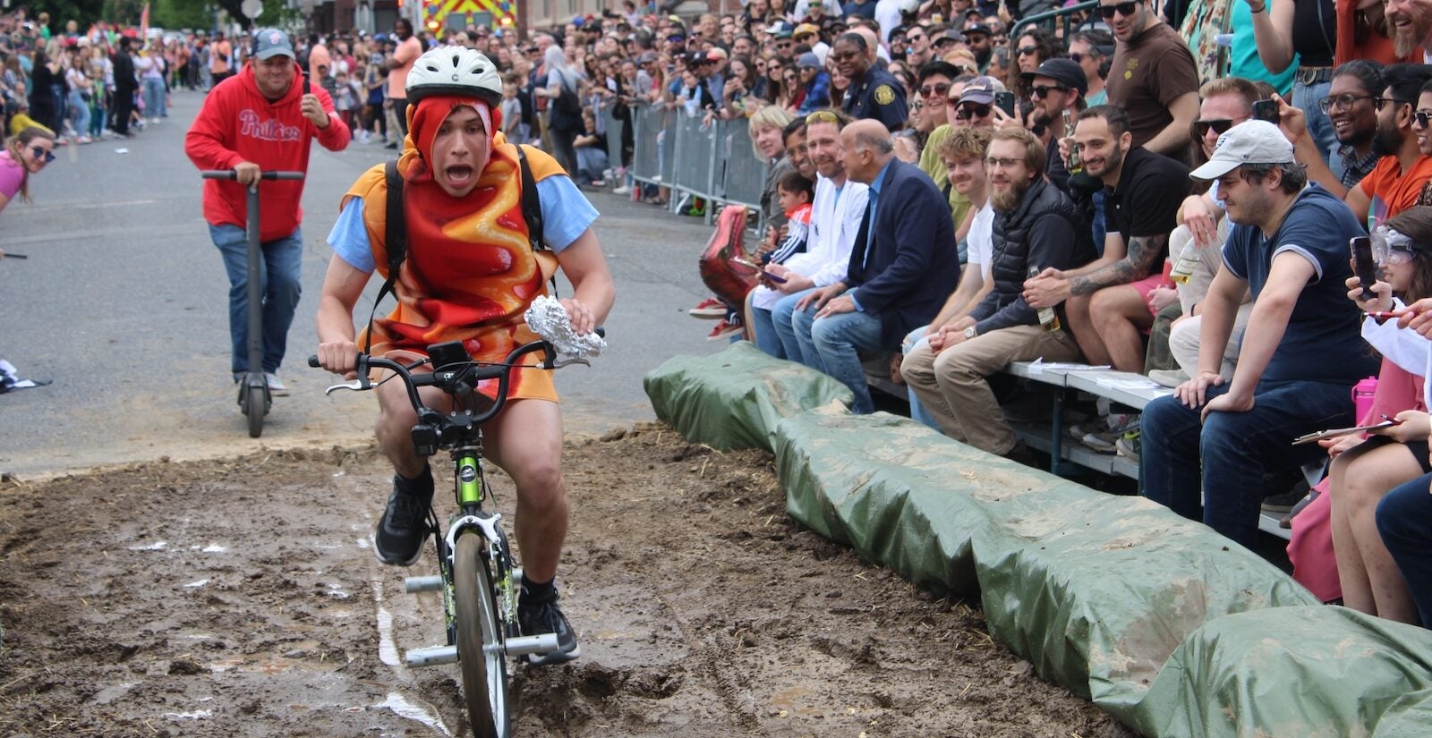 A person dressed as a hotdog rides through the mud pit at the Kensington Derby