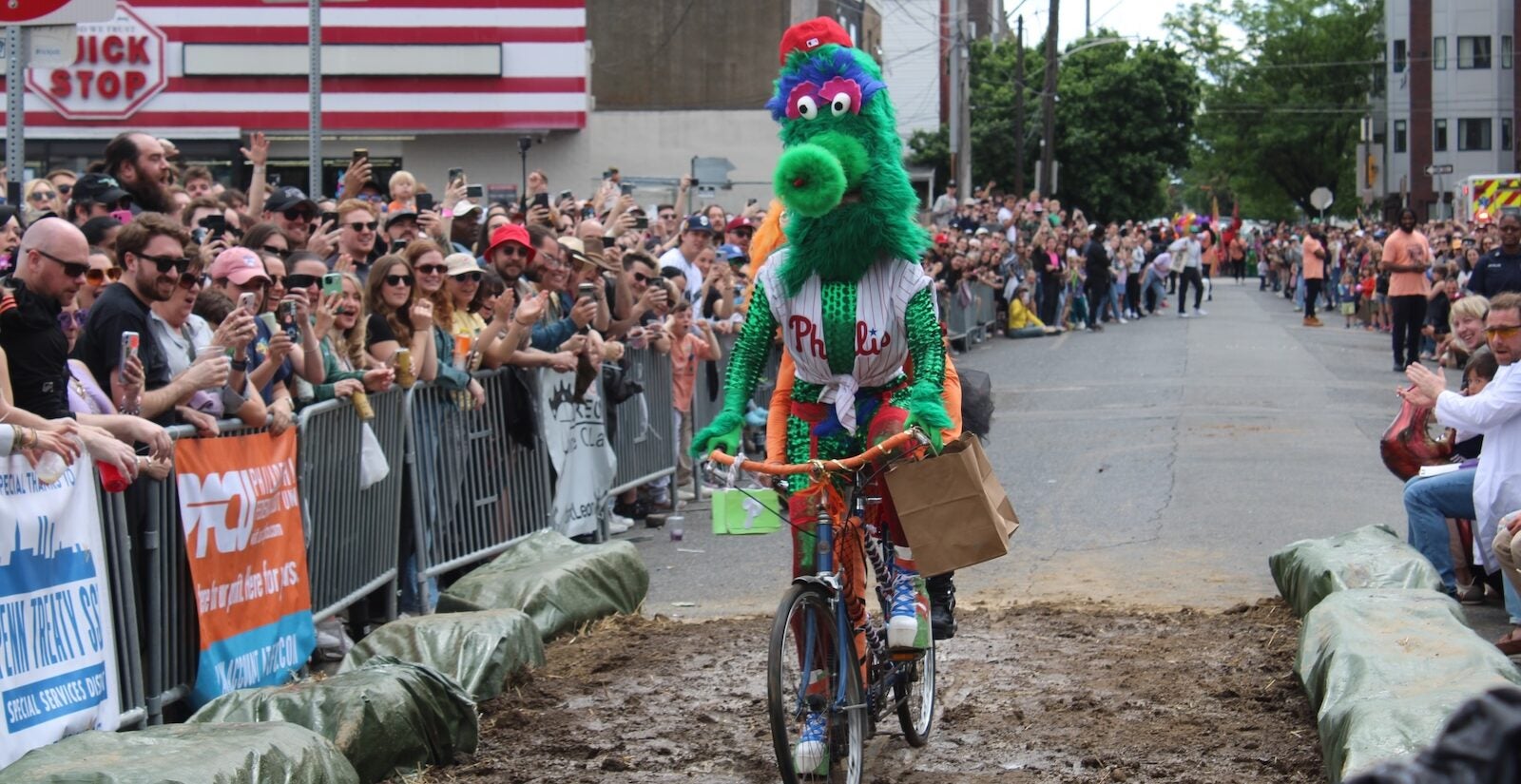 A glamorous Gritty and Phillie Phanatic make their way through the mud pit at the Kensington Derby