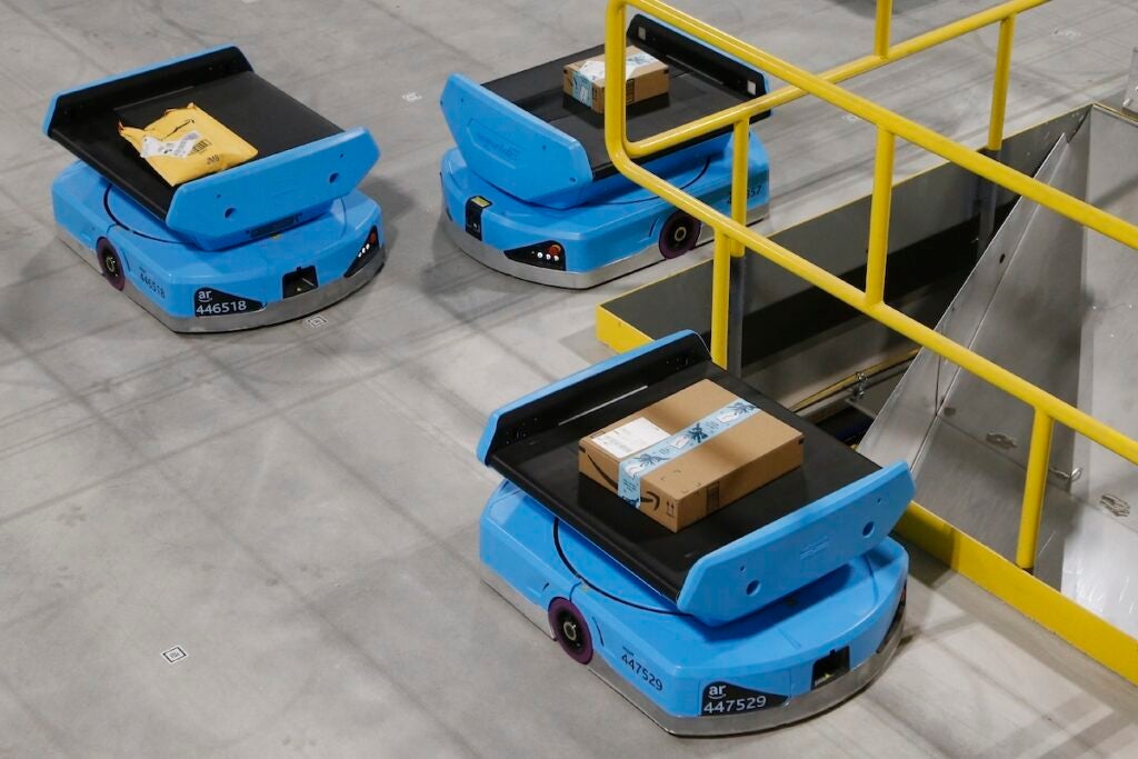 In this Dec. 17, 2019, file photo Amazon robots move along the warehouse floor with packages before finding the proper delivery chute at an Amazon warehouse facility in Goodyear, Ariz. (AP Photo/Ross D. Franklin, File)